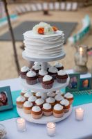 A silbolic wedding cake on the top and cupckes for erevyone